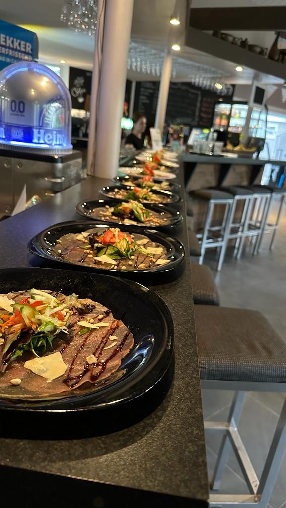 Een lange rij borden met carpaccio